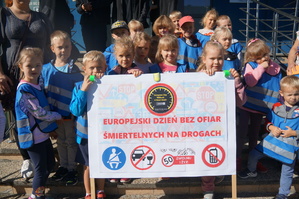 przedszkolaki trzymają baner z hasłem akcji zdjęcie kolorowe zrobione przed budynkiem komendy
