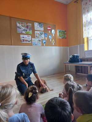 policjantka pokazuje dzieciom pozycję jaką należy przyjąć w kontakcie z niebezpiecznym psem