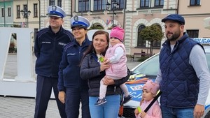 na tle radiowozu stoi rodzina z dziećmi obok policjanci