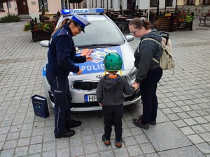 policjantka wręcza odblask dziecku obok stoi matka