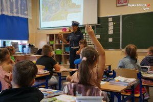 na pierwszym planie zgłaszająca się uczennica w tle policjantka