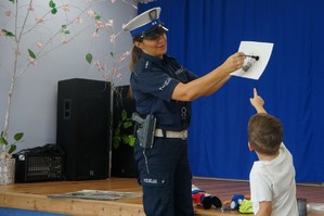 policjantka pokazuje w jaki sposób zabezpiecza się odbitki linii papilarnych chłopczyk stoi koło niej