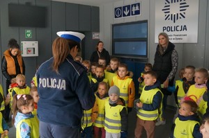 zdjęcie kolorowe zrobione w pomieszczeniach komendy policjantka stoi tyłem przed nią dzieci