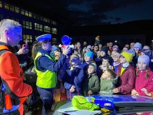 policjantka pokazuje maskotkę cpr ratusia i tłumaczy dzieciom jak wezwać pomoc