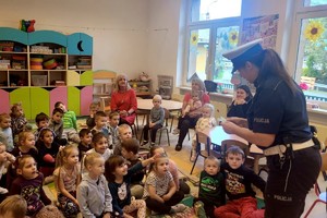 policjantka rozdaje przedszkolakom zawieszki odblaskowe