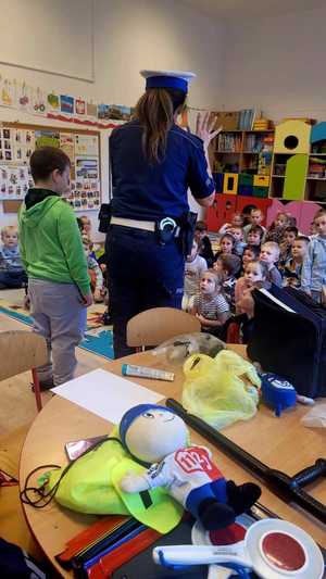 policjantka i chłopczyk stoją tyłem w tle pozostałe przedszkolaki
