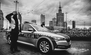 zdjęcie czarno-białe policjanci stoją obok radiowozu i oddają honor