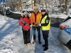 policjantka z kobietą i mężczyzną na zdjęciu trzymają odblaski w tle ulica