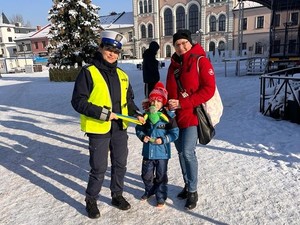 policjantka na zdjęciu z kobietą i dzieckiem trzymają odblask