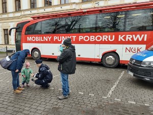 policjantka daje odblask dziecku w tle bus do poboru krwi