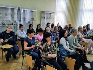 zdjęcie grupowe na sali siedzą kobiety trzymają kwiaty
