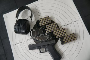 pistole naboje słuchawki i okulary leżące na tarczy