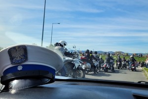 zdjęcie kolorowe zrobione z wnętrza radiowozu na pierwszym planie czapka policyjna w tle motocykliści