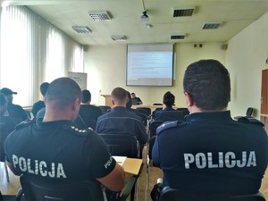 zdjęcie kolorowe policjanci siedzą tyłem i piszą test