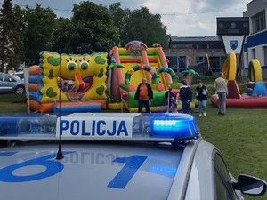 zdjęcie kolorowe na pierwszym planie fragment radiowozu w tle dmuchańce