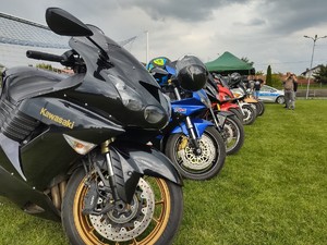 zdjęcie kolorowe na pierwszym planie zaparkowane motocykle w tle stoisko policyjne i radiowóz