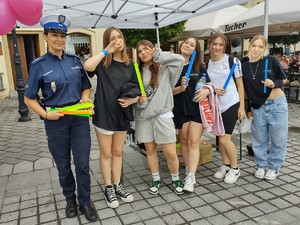 zdjecie kolorowe policjantka stoi a obok niej dziewczyny które trzymają odblaski