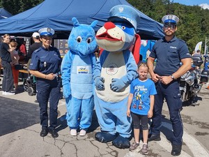 zdjęcie kolorowe maskotki policjanci i dziewczynka stoją koło siebie