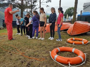 zdjęcie kolorowe na pierwszym planie na ziemi leżą koła ratunkowe uczniowie stoją obok przed nimi ratownik