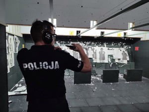 zdjęcie kolorowe policjant pokazuje broń do przejrzenia instruktorowi