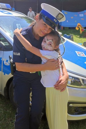 zdjęcie kolorowe policjantka przytula się z dziewczynką
