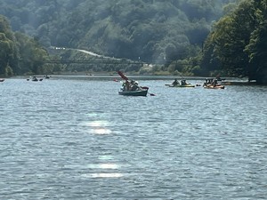 zdjęcie kolorowe, kajakarze płynący po jeziorze, w tle góry