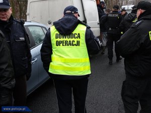 kolorowe zdjęcie poglądowe przedstawiające policjanta stojącego tyłem