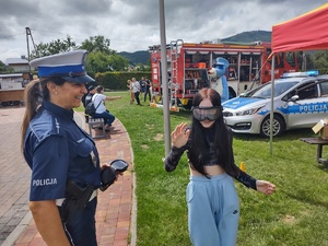 zdjęcie kolorowe policjantka obok niej dziewczyna w założonych alkogooglach pokonuje slalom