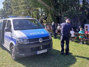 kolorowe zdjęcie radiowozu w tle policjantka, policjant i dzieci