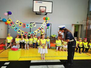 zdjęcie kolorowe policjantka uczy dzieci jak przechodzi się przez jezdnię