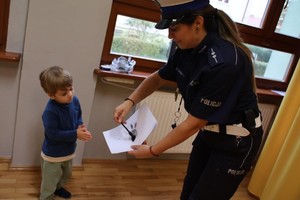 zdjęcie kolorowe policjantka pokazuje jak zabezpiecza się odciski linii papilarnych