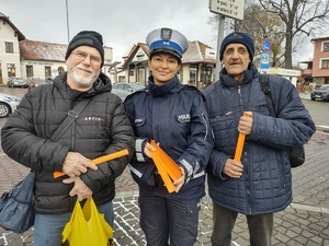 zdjęcie kolorowe policjantka oraz dwóch pieszych którzy trzymają odblaski