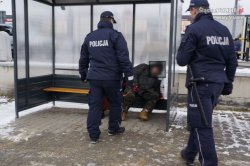 zdjęcie poglądowe osoba nietrzeźwa siedzi na przystanki podchodzą do niej policjanci