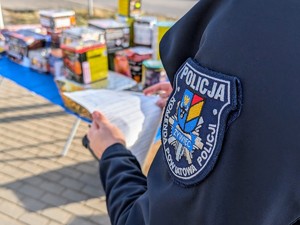 zdjęcie kolorowe fragment policjanta podczas kontroli stosika z fajerwerkami