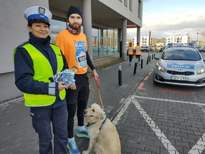 zdjęcie kolorowe policjantka stoi obok biegacza w tle radiowóz