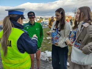 zdjęcie kolorowe policjantka wręcza odblaski wolontariuszom wośp