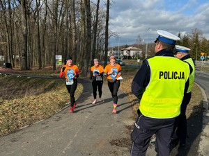 zdjęcie kolorowe policjanci stoją tyłem w tle biegacze