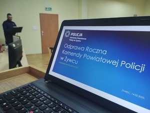 zdjęcie kolorowe laptop ze slajdem w tle policjant