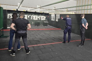 policjanci podczas strzelania obok stoją instruktorzy