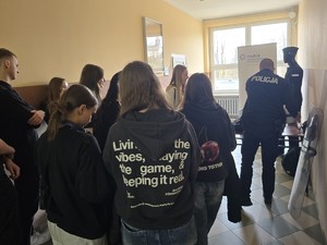 policjant wraz z uczniami na policyjnym stoisku