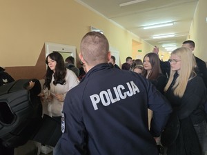 policjanci podczas prezentacji sprzętu w tle uczniowie