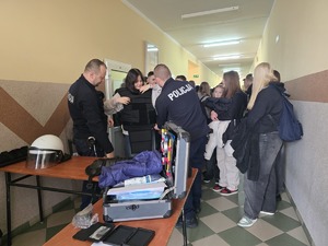 policjanci podczas prezentacji sprzętu w tle uczniowie