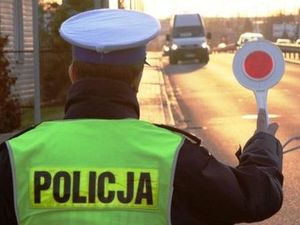 zdjęcie poglądowe policjant tyłem zatrzymuje pojazd tarczą do zatrzymywania pojazdów