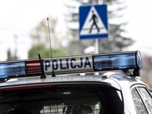 zdjęcie fragmentu radiowozu i znaku drogowego oznaczającego przejście dla pieszych