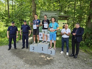 odznaczeni biegacze stoją na podium obok goście