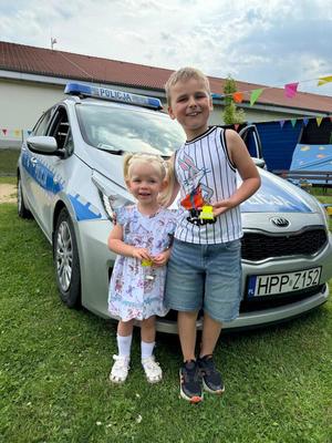 chłopczyk i dziewczynka na tle radiowozu