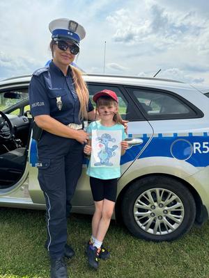 policjantka i dziewczynka stoją na tle radiowozu