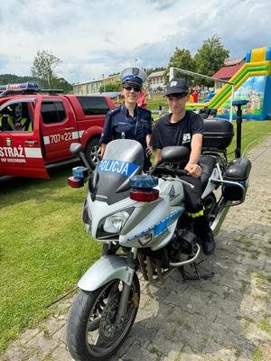 chłopak siedzi na policyjnym motocyklu obok stoi policjantka