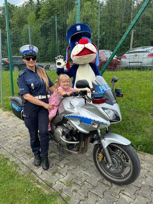 dziewczynka siedzi na policyjnym motocyklu obok stoi policjanta