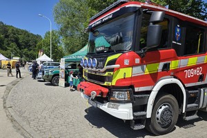 na pierwszym planie samochód straży pożarnej w tle stoiska służb